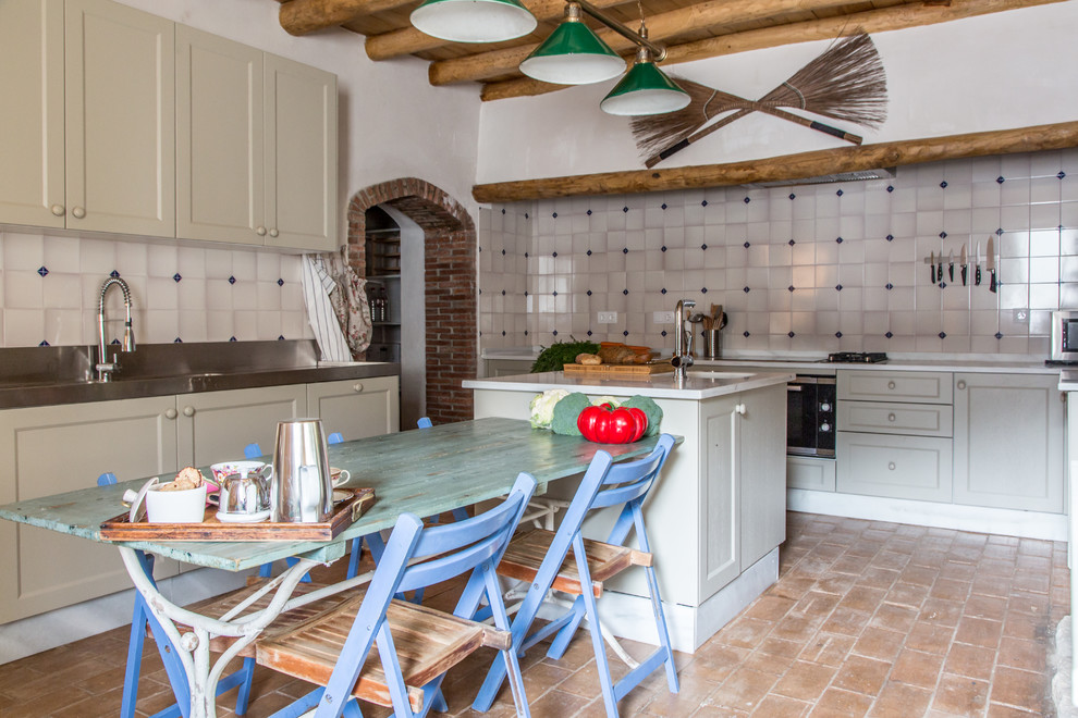 Diseño de cocina de estilo de casa de campo de tamaño medio con electrodomésticos de acero inoxidable, suelo de baldosas de terracota y una isla