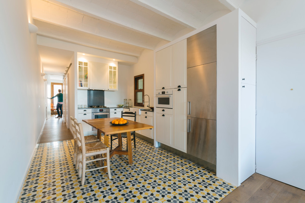 Mittelgroße Nordische Wohnküche ohne Insel in L-Form mit Waschbecken, profilierten Schrankfronten, weißen Schränken, Küchengeräten aus Edelstahl und Keramikboden in Barcelona