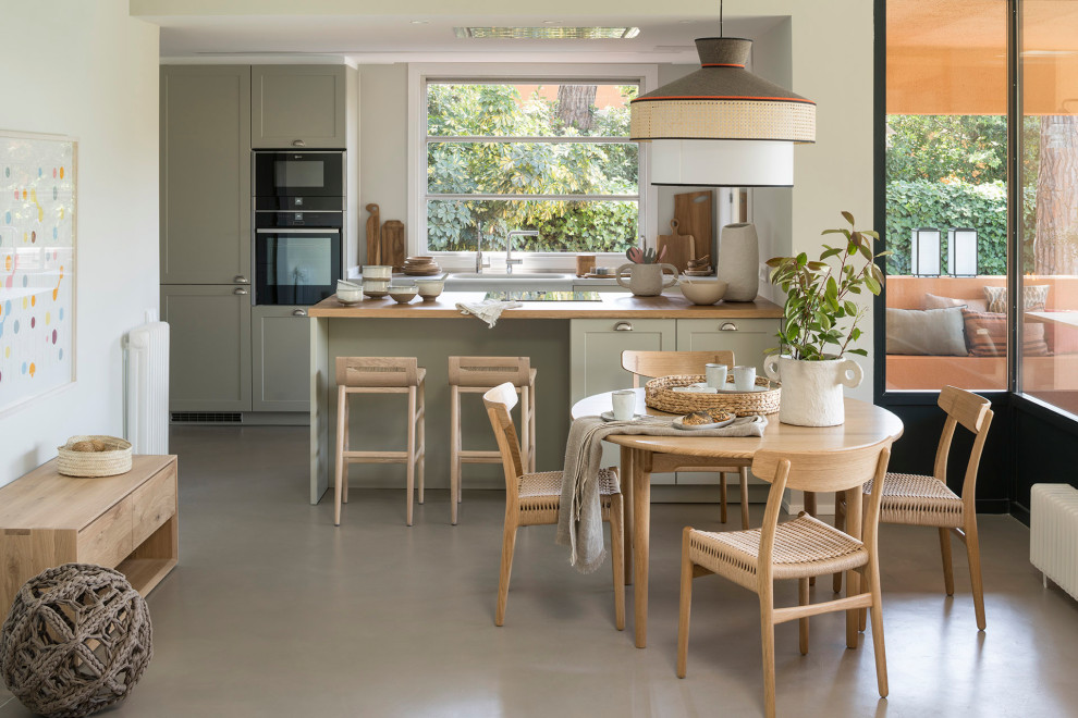 Идея дизайна: кухня среднего размера в средиземноморском стиле с серыми фасадами, деревянной столешницей, бетонным полом, полуостровом, серым полом, обеденным столом, врезной мойкой, фасадами в стиле шейкер и черной техникой