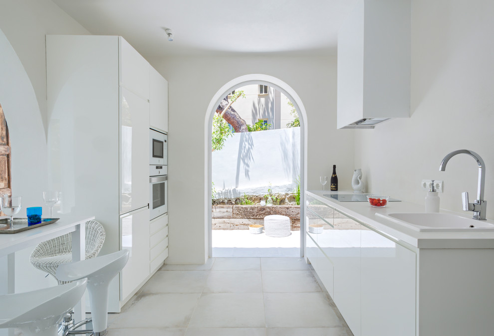 Kitchen - mediterranean single-wall kitchen idea in Other with flat-panel cabinets, white cabinets, an island and white countertops