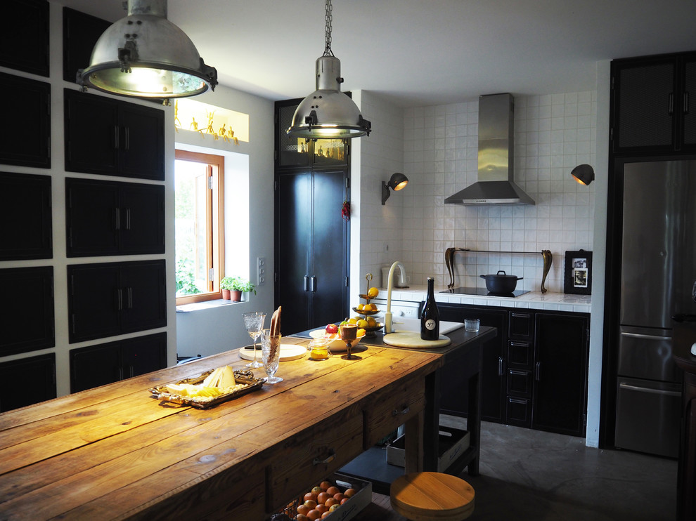 Foto de cocina lineal industrial de tamaño medio abierta y de obra con armarios con paneles lisos, una isla y puertas de armario negras