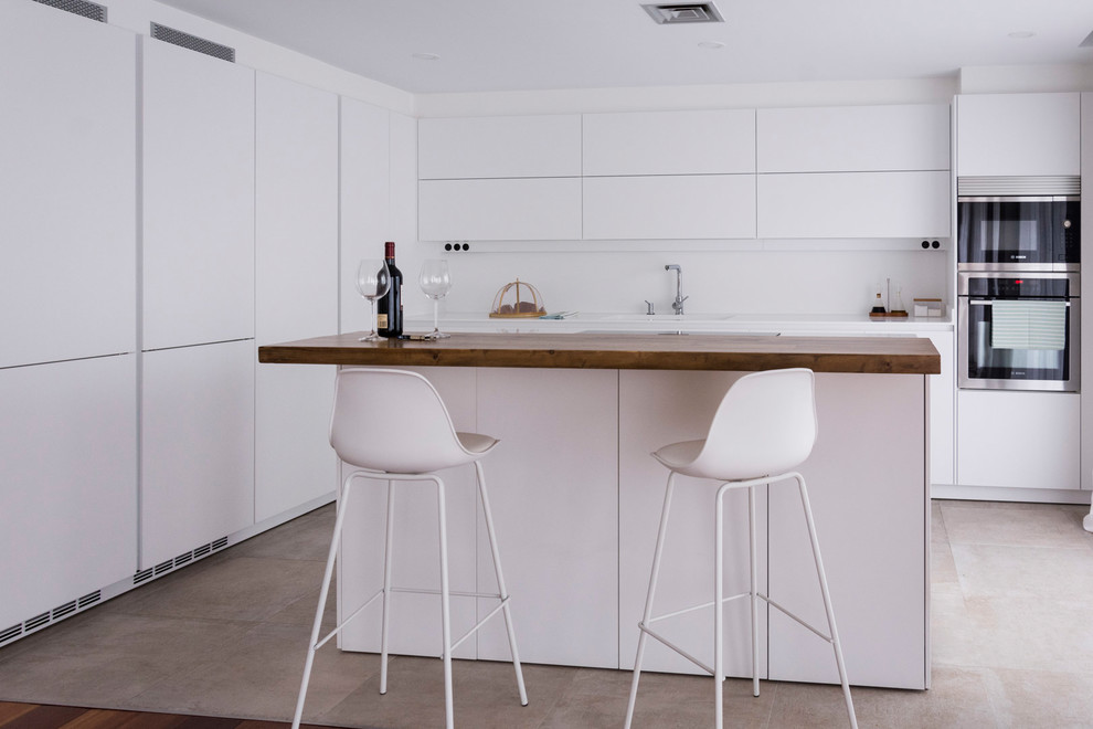 Diseño de cocina minimalista con fregadero integrado, armarios con paneles lisos, puertas de armario blancas, salpicadero blanco, una isla y encimeras blancas