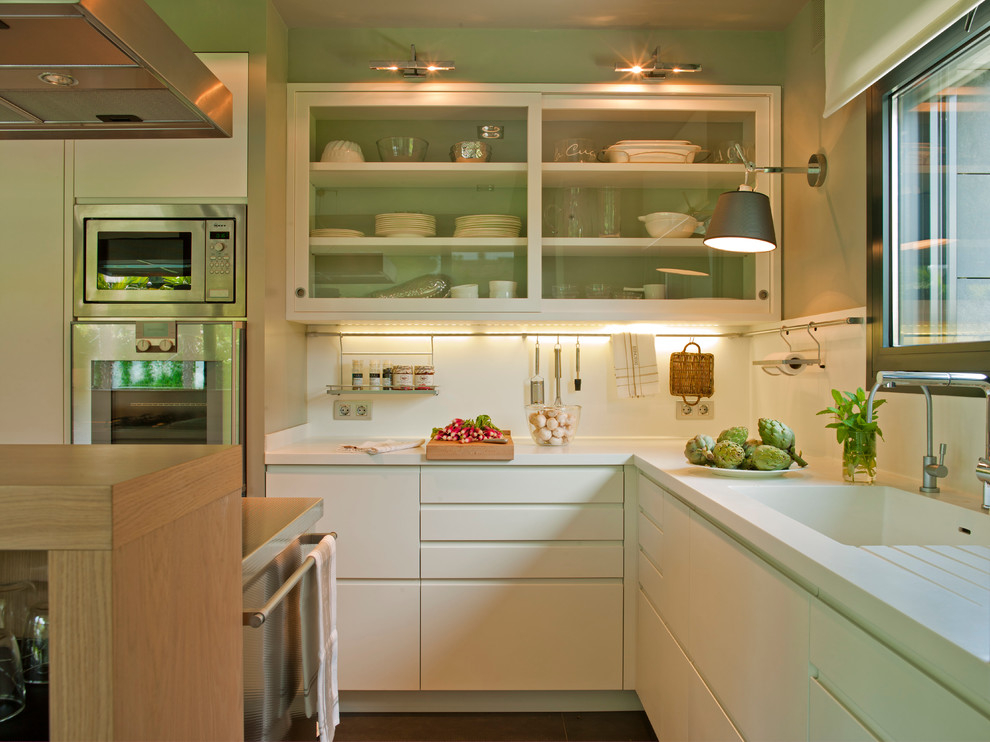 Exempel på ett avskilt, mellanstort modernt l-kök, med vita skåp, vitt stänkskydd, rostfria vitvaror, en integrerad diskho, luckor med glaspanel, bänkskiva i koppar och en köksö
