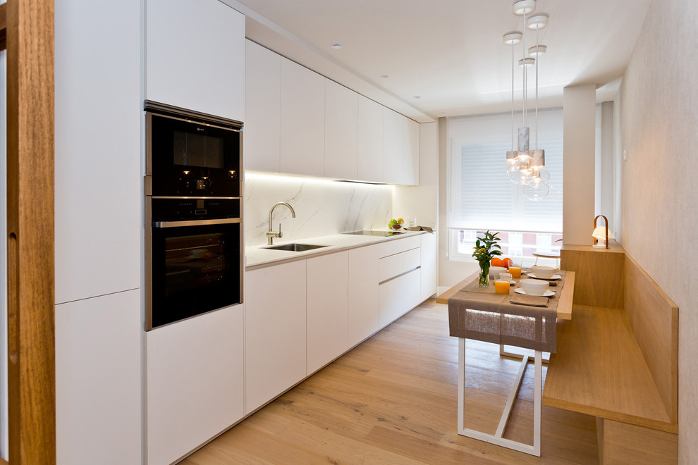 Imagen de cocina comedor lineal actual con armarios con paneles lisos, puertas de armario blancas, salpicadero blanco, suelo de madera en tonos medios y encimeras blancas