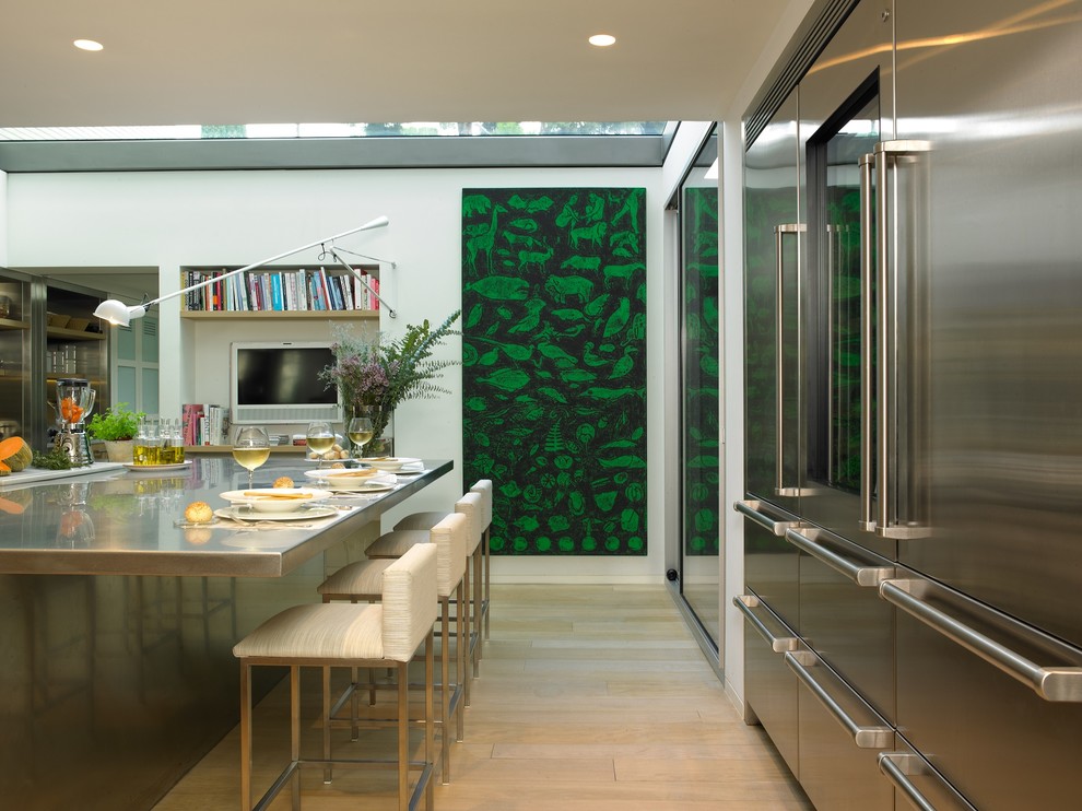 バルセロナにある広いコンテンポラリースタイルのおしゃれなキッチン (シルバーの調理設備、淡色無垢フローリング、フラットパネル扉のキャビネット、ステンレスキャビネット) の写真