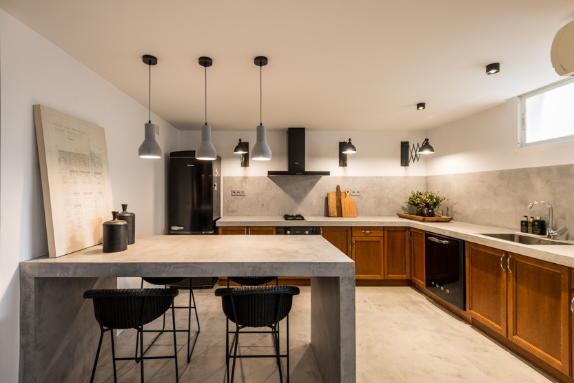 This is an example of a rustic l-shaped kitchen/diner in Alicante-Costa Blanca with beaded cabinets, medium wood cabinets, concrete worktops, black appliances, concrete flooring and an island.