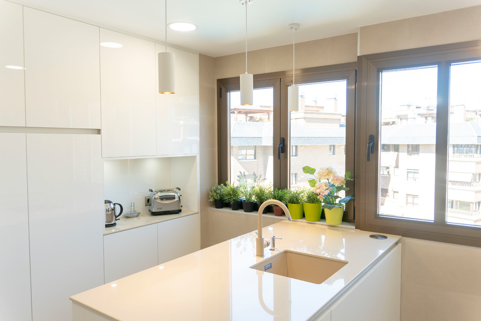 Foto på ett mellanstort funkis u-kök, med släta luckor, vita skåp, beige stänkskydd, betonggolv och en halv köksö