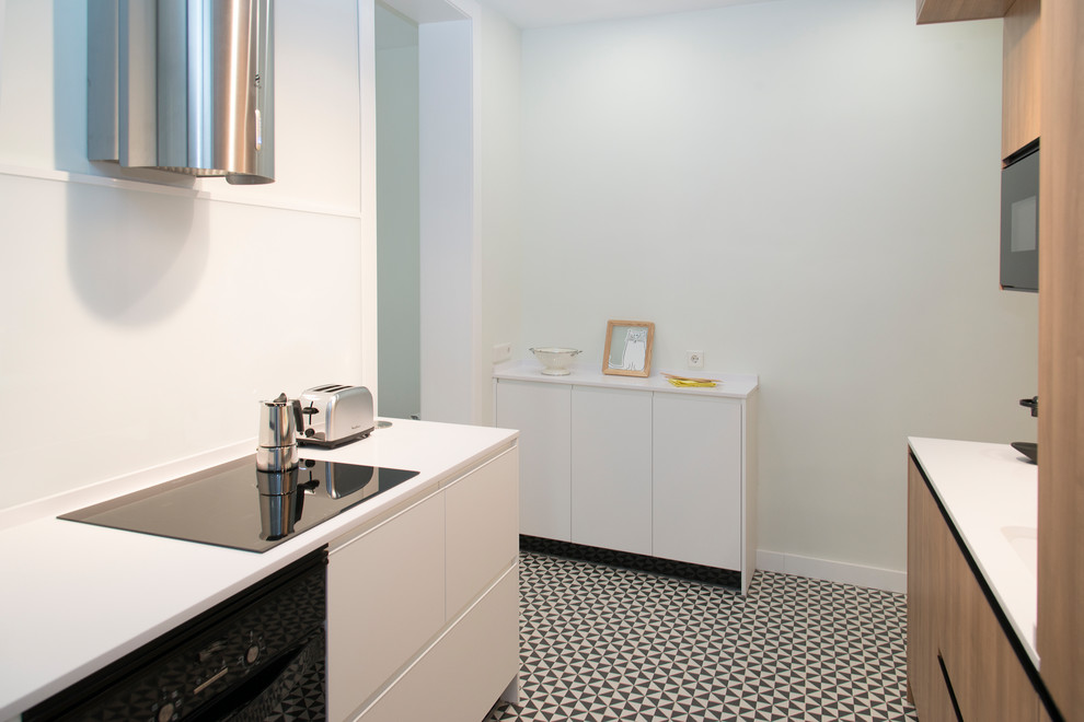 Small modern single-wall enclosed kitchen in Madrid with a submerged sink, flat-panel cabinets, white cabinets, engineered stone countertops, white splashback, window splashback, black appliances, ceramic flooring, no island and multi-coloured floors.