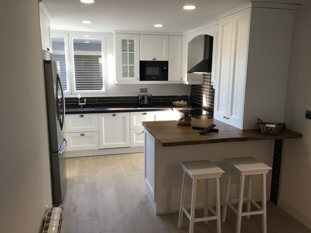 Mid-sized elegant u-shaped light wood floor eat-in kitchen photo in Madrid with an undermount sink, beaded inset cabinets, white cabinets, quartz countertops, black backsplash, ceramic backsplash, stainless steel appliances and an island