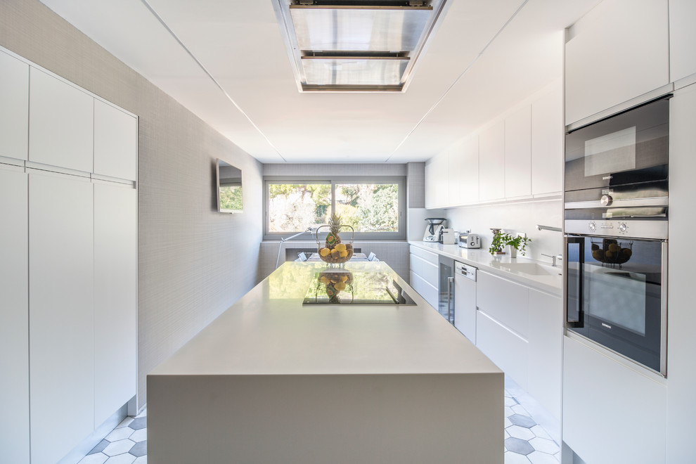 Große Moderne Wohnküche mit integriertem Waschbecken, flächenbündigen Schrankfronten, weißen Schränken, Küchenrückwand in Weiß, Küchengeräten aus Edelstahl und Kücheninsel in Barcelona