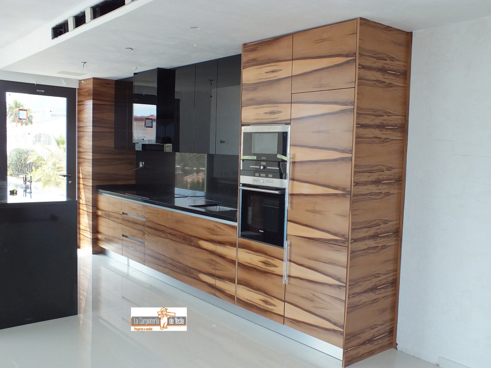 Photo of a medium sized contemporary u-shaped kitchen/diner in Alicante-Costa Blanca with a submerged sink, recessed-panel cabinets, marble splashback, integrated appliances, ceramic flooring, an island, beige floors, black worktops and a drop ceiling.