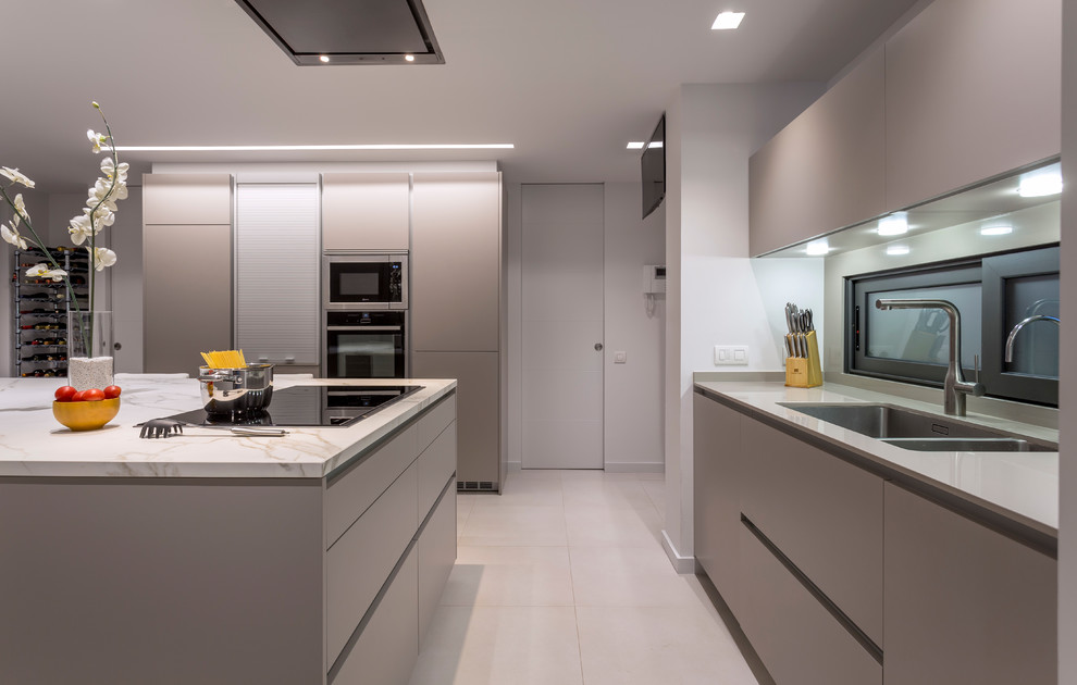 Photo of a large contemporary u-shaped open plan kitchen in Barcelona with a double-bowl sink, flat-panel cabinets, beige cabinets, stainless steel appliances, ceramic flooring, an island and beige floors.