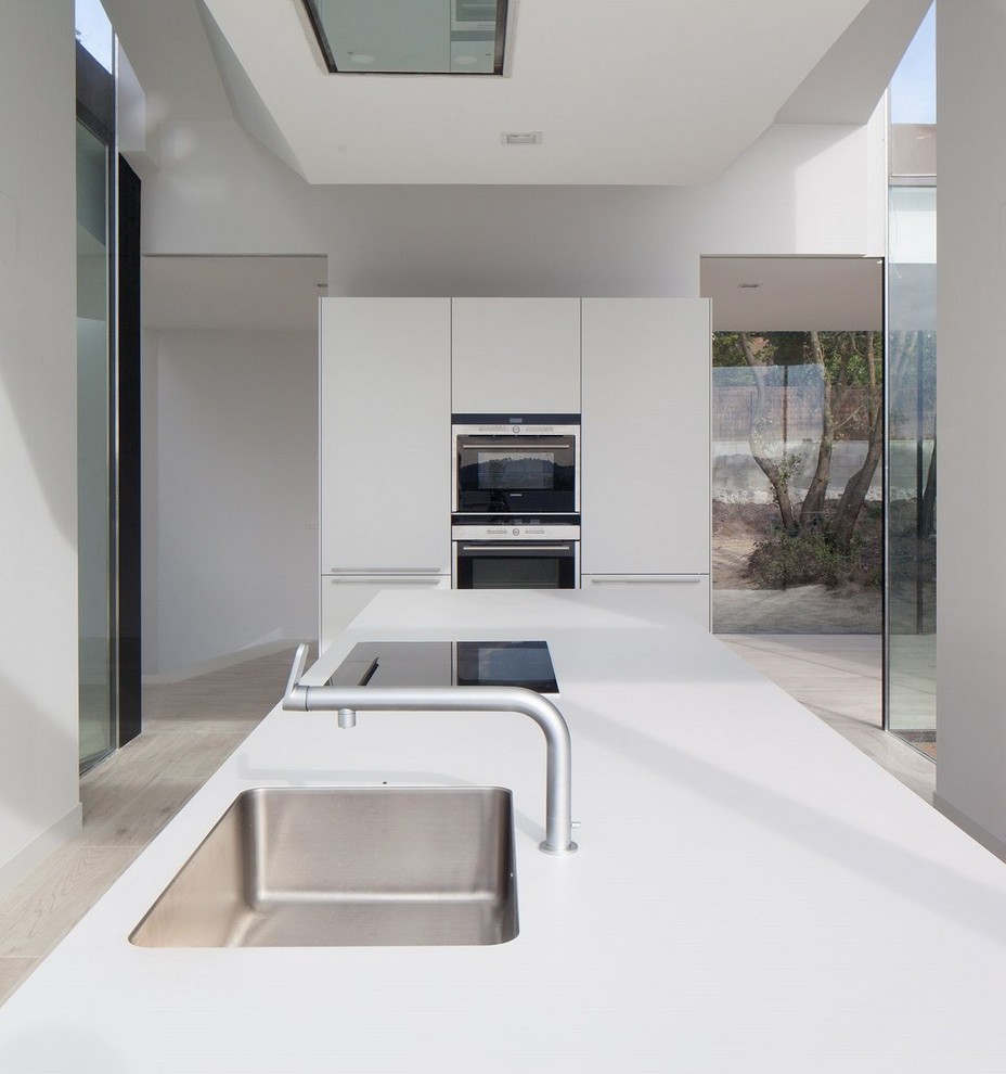 Immagine di una grande cucina design con ante lisce, ante bianche, elettrodomestici in acciaio inossidabile e top in quarzo composito