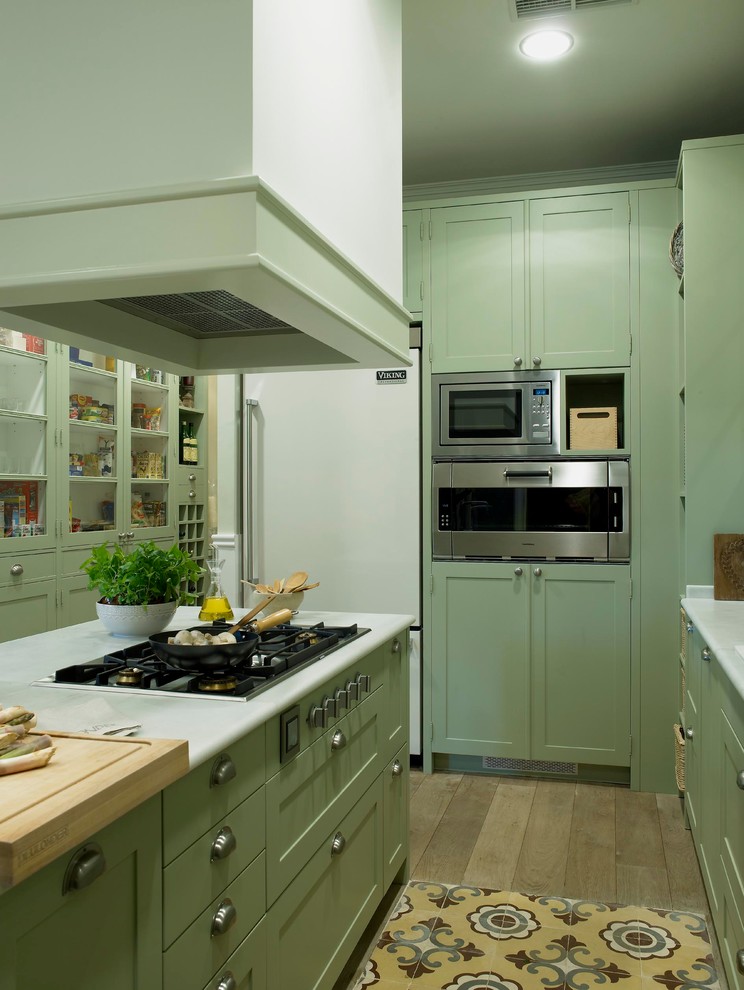 This is an example of a medium sized country single-wall kitchen/diner in Barcelona with recessed-panel cabinets, green cabinets and an island.