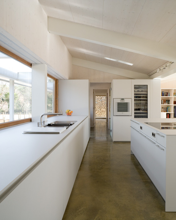 Пример оригинального дизайна: большая прямая кухня-гостиная в современном стиле с двойной мойкой, плоскими фасадами, белыми фасадами, белой техникой, бетонным полом и островом