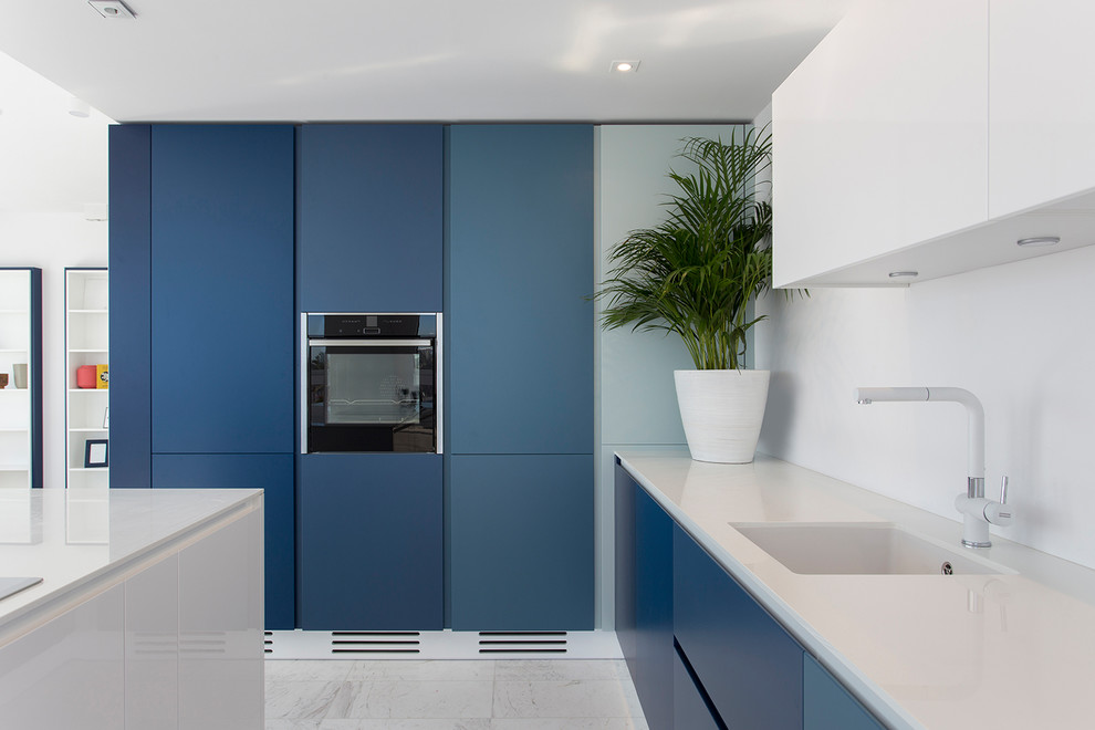 This is an example of a coastal kitchen in Other with a single-bowl sink, flat-panel cabinets, blue cabinets, an island, white floors and white worktops.
