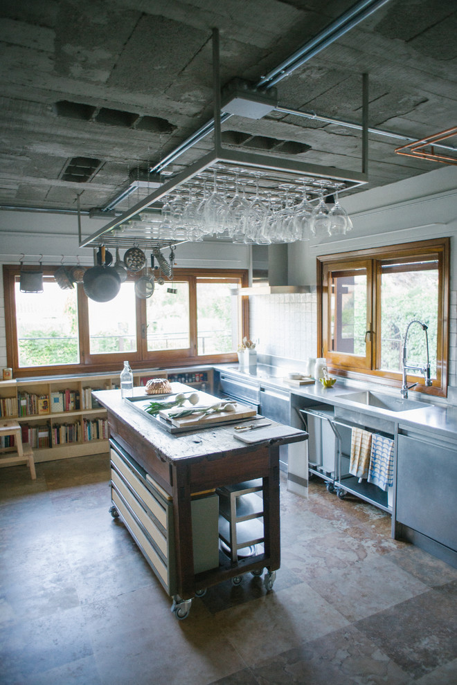 Foto di una grande cucina industriale con lavello integrato, nessun'anta, ante in legno chiaro, top in acciaio inossidabile e paraspruzzi bianco