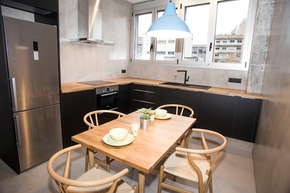 Стильный дизайн: угловая кухня среднего размера в стиле лофт с обеденным столом, черными фасадами, деревянной столешницей, серым полом и бетонным полом без острова - последний тренд