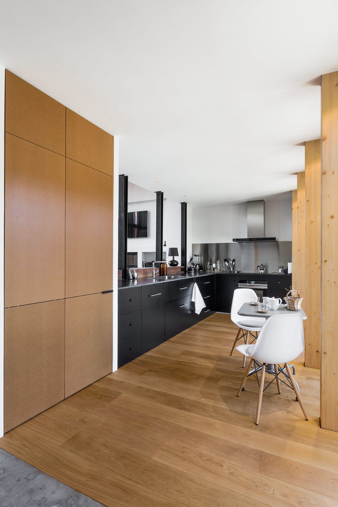 Idéer för mellanstora funkis grått kök, med en undermonterad diskho, släta luckor, svarta skåp, granitbänkskiva, stänkskydd med metallisk yta, integrerade vitvaror, mellanmörkt trägolv och brunt golv