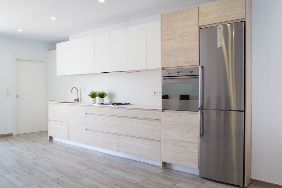 Photo of a medium sized modern single-wall kitchen/diner in Other with a submerged sink, raised-panel cabinets, light wood cabinets, engineered stone countertops, white splashback, stainless steel appliances, ceramic flooring, grey floors and white worktops.