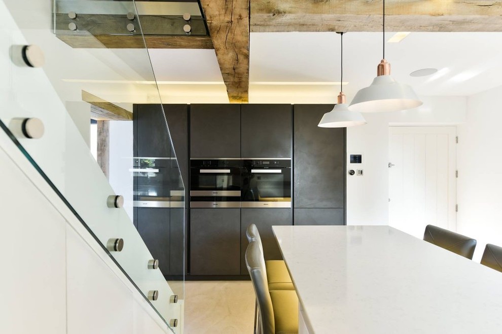 Medium sized contemporary u-shaped open plan kitchen in London with flat-panel cabinets, grey cabinets, engineered stone countertops, stainless steel appliances, concrete flooring, an island and beige floors.