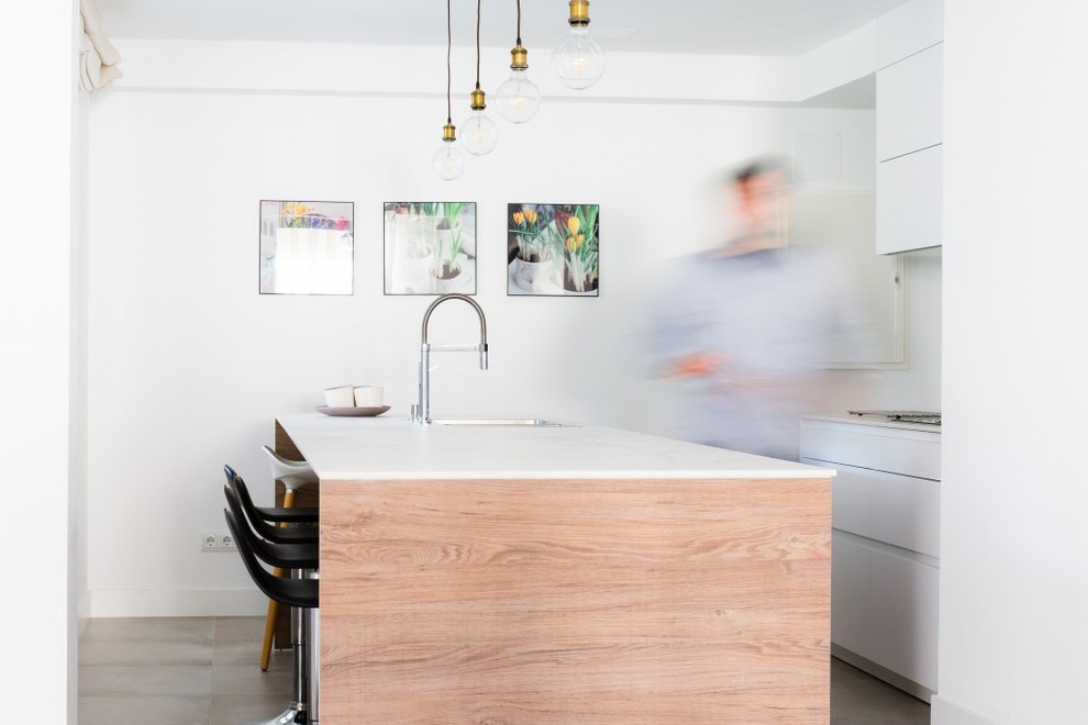 Moderne Küche mit Unterbauwaschbecken, flächenbündigen Schrankfronten, weißen Schränken, Küchenrückwand in Weiß, Kücheninsel, grauem Boden und weißer Arbeitsplatte in Sonstige