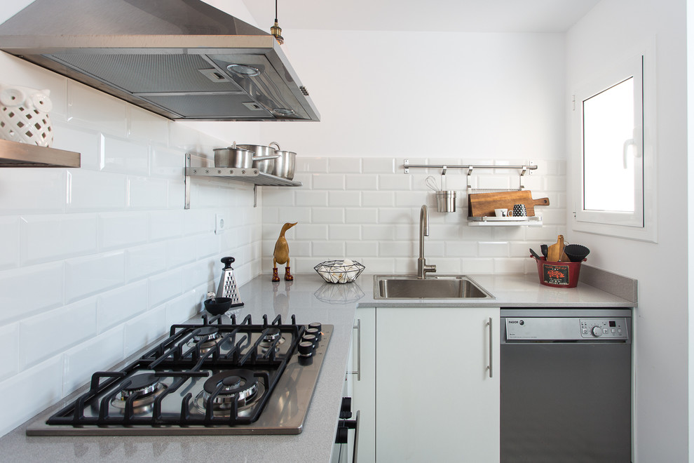 Small urban l-shaped enclosed kitchen photo in Barcelona with a drop-in sink, flat-panel cabinets, white cabinets, solid surface countertops, white backsplash, subway tile backsplash, stainless steel appliances, no island and gray countertops