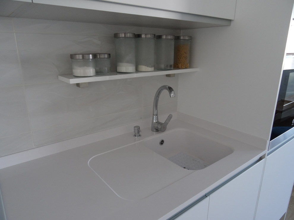 Offene, Einzeilige, Kleine Moderne Küche ohne Insel mit integriertem Waschbecken, weißen Schränken, Quarzwerkstein-Arbeitsplatte und flächenbündigen Schrankfronten in Alicante-Costa Blanca