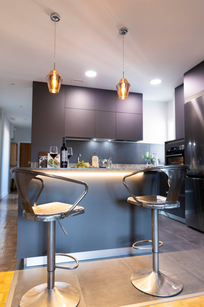 Ejemplo de cocina moderna de tamaño medio con puertas de armario grises, encimera de granito y electrodomésticos de acero inoxidable