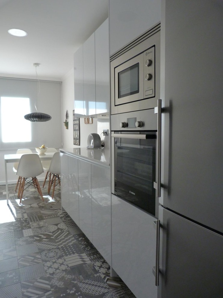 Medium sized contemporary galley kitchen/diner in Other with flat-panel cabinets, white cabinets, white splashback, stainless steel appliances, no island, an integrated sink, engineered stone countertops and ceramic flooring.