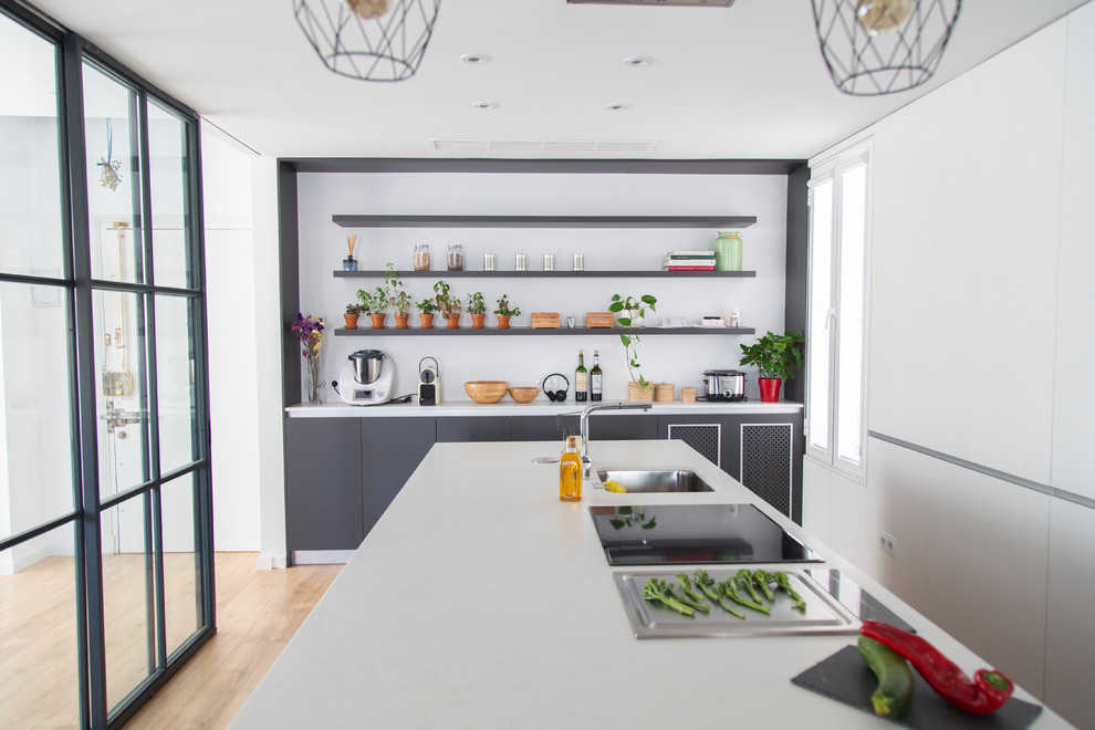 Modern inredning av ett avskilt, stort vit vitt kök, med vita skåp, bänkskiva i kvarts, en köksö, en undermonterad diskho, släta luckor, ljust trägolv och beiget golv