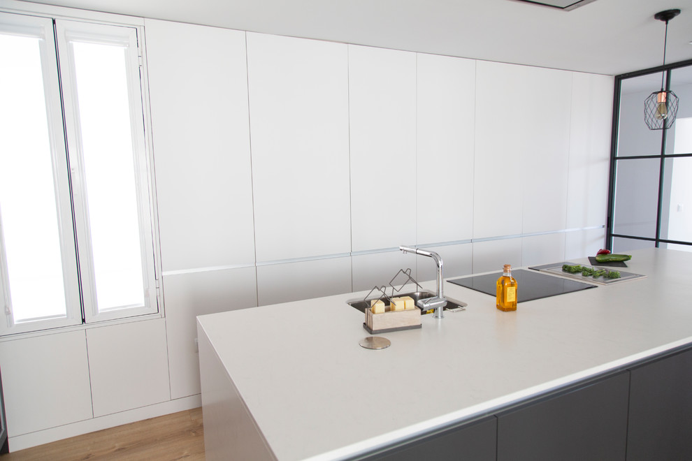 Bild på ett avskilt, stort funkis vit vitt kök, med en rustik diskho, vita skåp, bänkskiva i kvarts, stänkskydd med metallisk yta, stänkskydd i metallkakel, rostfria vitvaror och en köksö