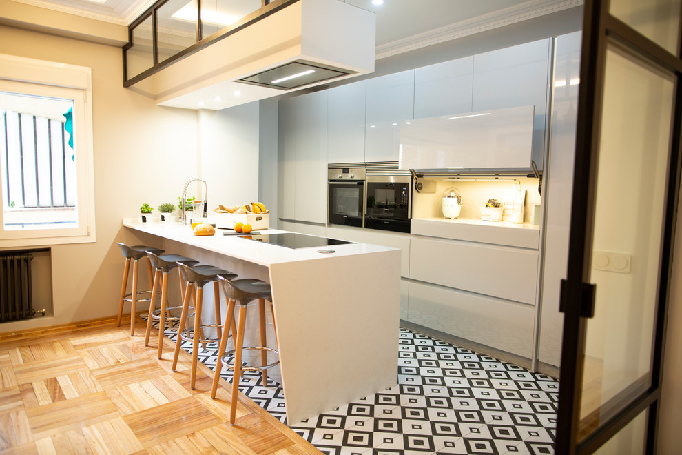 Example of a large trendy single-wall ceramic tile and multicolored floor kitchen design in Madrid with a double-bowl sink, gray cabinets, metallic backsplash, stainless steel appliances, an island and white countertops