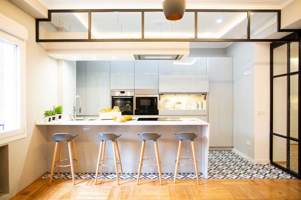 Eat-in kitchen - large contemporary single-wall ceramic tile and multicolored floor eat-in kitchen idea in Madrid with a double-bowl sink, gray cabinets, metallic backsplash, stainless steel appliances, an island and white countertops