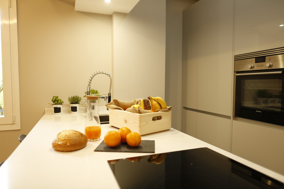 Example of a large minimalist single-wall ceramic tile and multicolored floor kitchen design in Madrid with a double-bowl sink, gray cabinets, metallic backsplash, stainless steel appliances, an island and white countertops