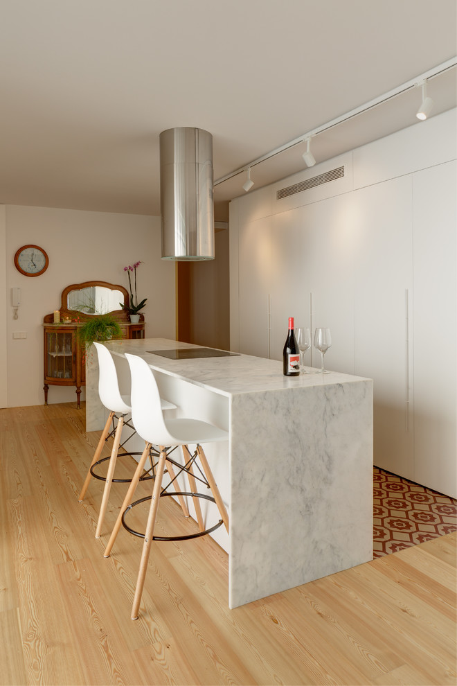Idéer för att renovera ett funkis vit vitt kök med öppen planlösning, med släta luckor, vita skåp, marmorbänkskiva, ljust trägolv och en köksö