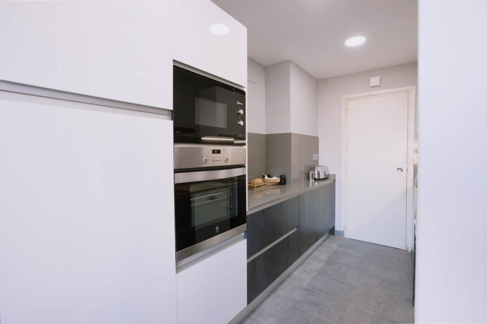Design ideas for a medium sized modern galley enclosed kitchen in Barcelona with a submerged sink, flat-panel cabinets, black cabinets, engineered stone countertops, grey splashback, engineered quartz splashback, stainless steel appliances, ceramic flooring, grey floors and grey worktops.