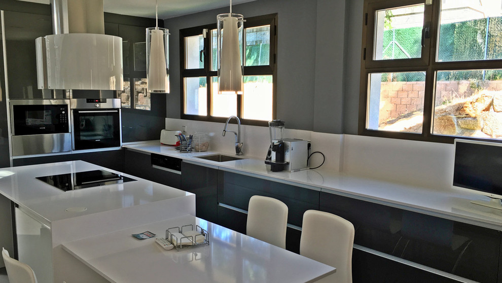 Immagine di una grande cucina contemporanea con lavello sottopiano, ante lisce, ante nere, paraspruzzi bianco e elettrodomestici in acciaio inossidabile