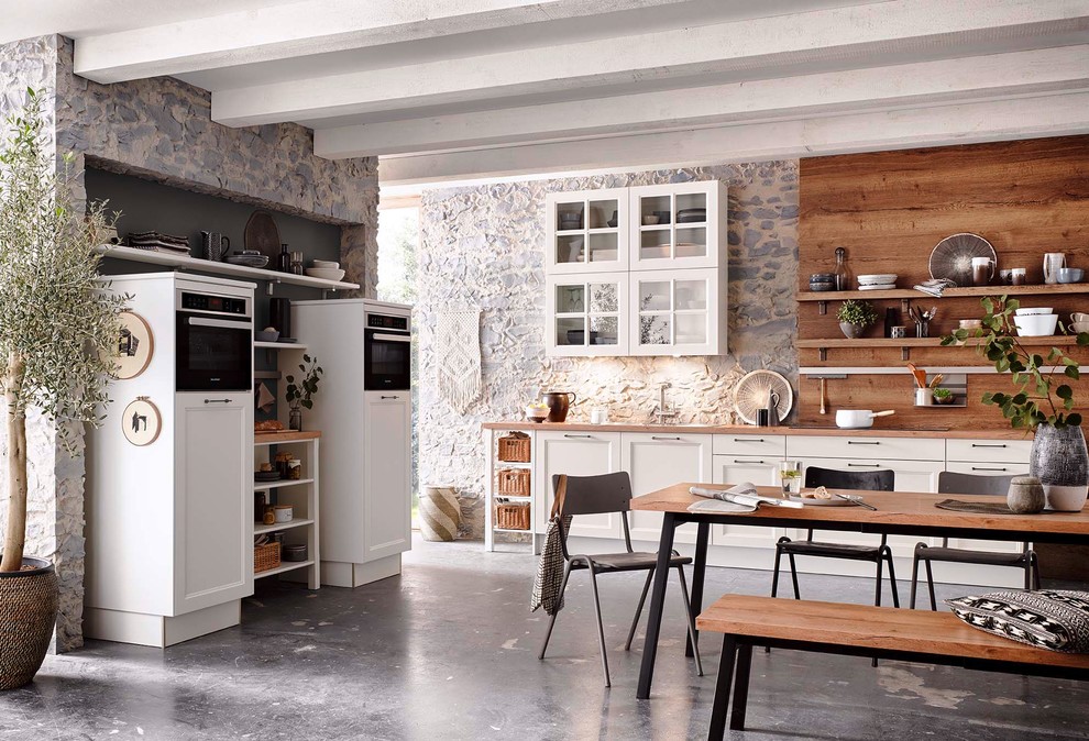 Diseño de cocina nórdica abierta con puertas de armario blancas, encimera de madera y salpicadero de madera
