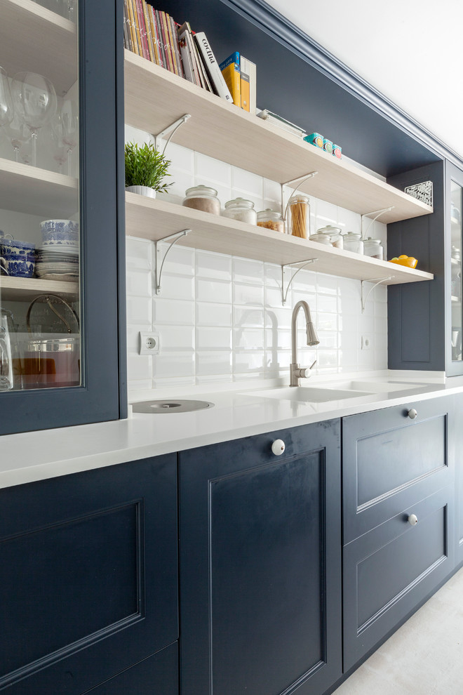 Aménagement d'une cuisine classique avec des portes de placard bleues, une crédence blanche, un plan de travail blanc, un évier 2 bacs et un placard à porte vitrée.