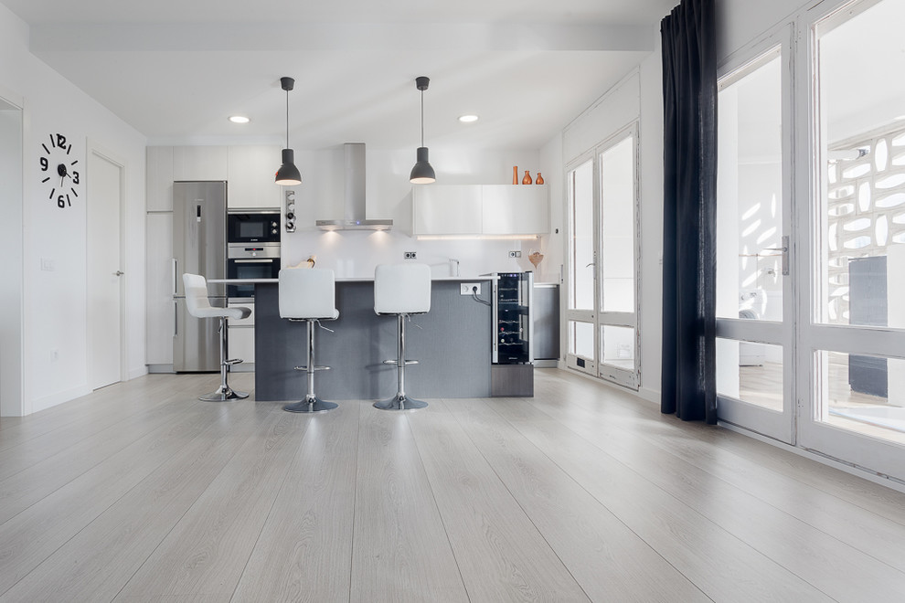 Immagine di una cucina contemporanea di medie dimensioni con ante lisce, ante grigie, paraspruzzi bianco, elettrodomestici in acciaio inossidabile e pavimento in legno massello medio