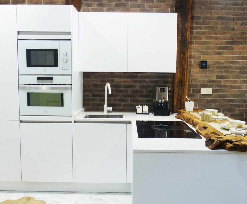 Cette photo montre une cuisine ouverte chic en L de taille moyenne avec des portes de placard blanches, un plan de travail en quartz modifié, une péninsule et un plan de travail blanc.