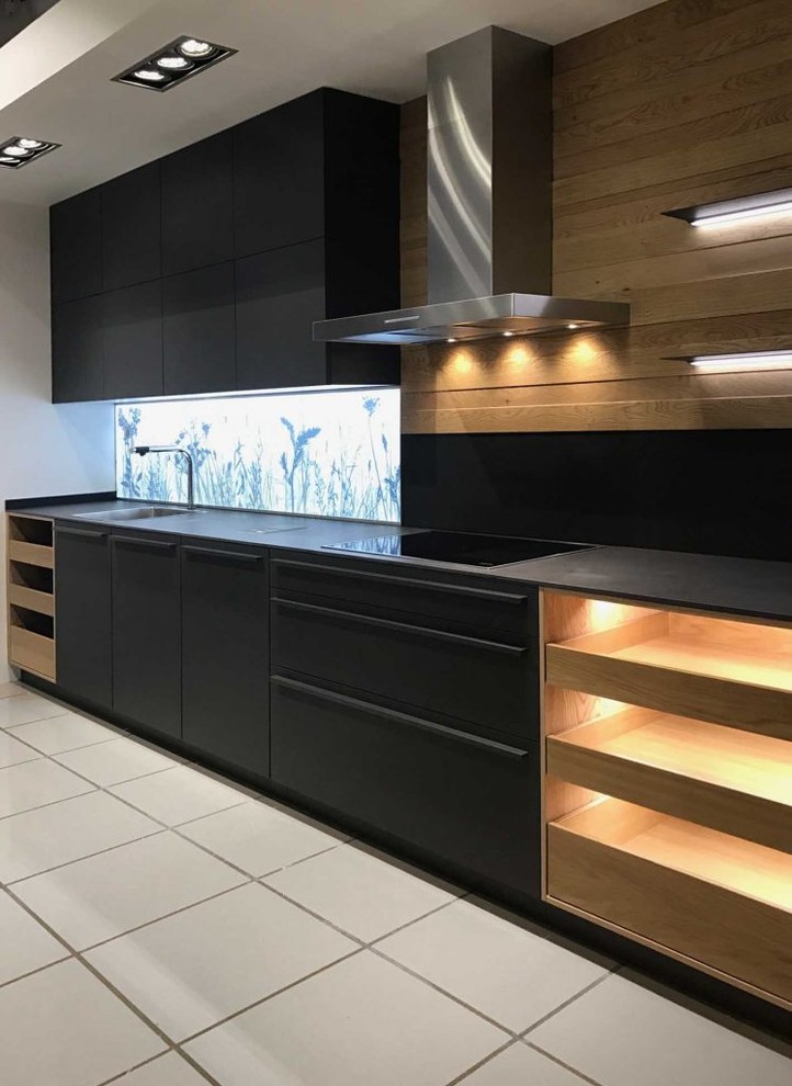 Inspiration for a medium sized contemporary l-shaped open plan kitchen in Madrid with flat-panel cabinets, black cabinets, engineered stone countertops, black appliances, porcelain flooring, an island and grey floors.