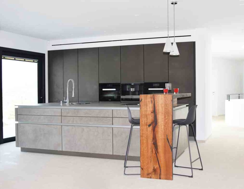 Cette photo montre une cuisine ouverte linéaire montagne de taille moyenne avec un placard à porte plane, un électroménager noir, sol en béton ciré, îlot et un sol gris.