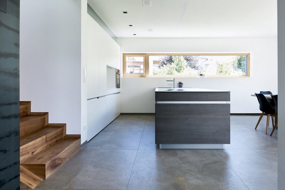 Esempio di una cucina minimalista di medie dimensioni con ante lisce, ante grigie, top in quarzo composito, elettrodomestici in acciaio inossidabile, pavimento in gres porcellanato e pavimento grigio