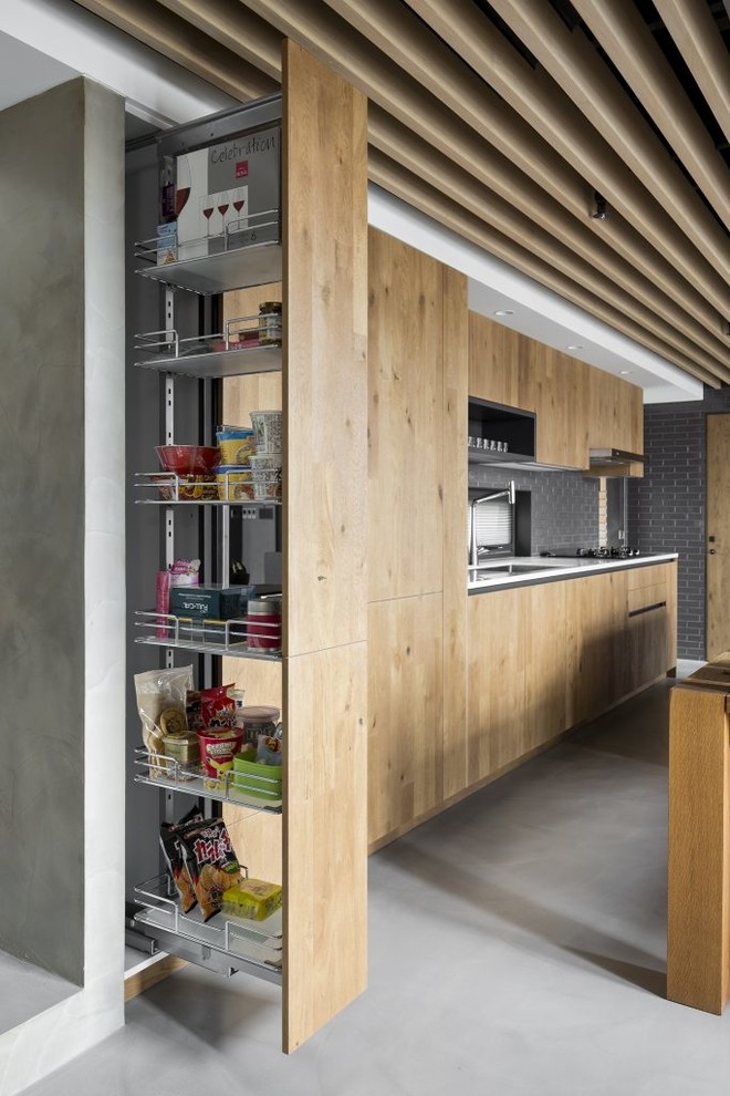 Imagen de cocina lineal contemporánea de tamaño medio abierta con puertas de armario de madera clara, encimera de cuarzo compacto, electrodomésticos de acero inoxidable, suelo de cemento, una isla y suelo gris