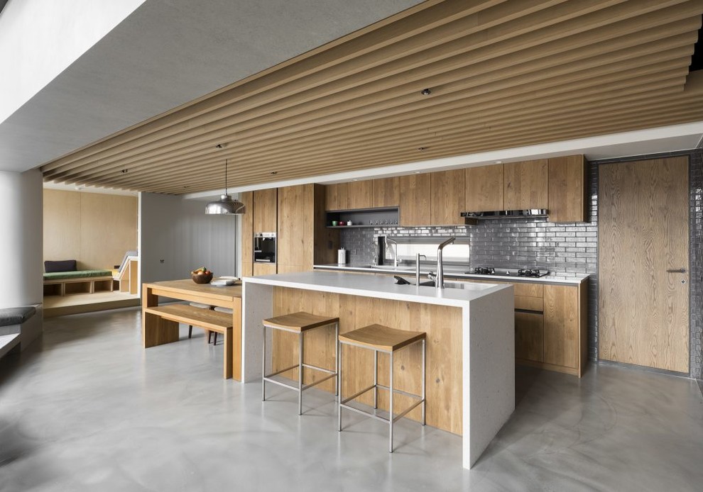 Ejemplo de cocina lineal contemporánea de tamaño medio abierta con puertas de armario de madera clara, encimera de cuarzo compacto, electrodomésticos de acero inoxidable, suelo de cemento, una isla y suelo gris
