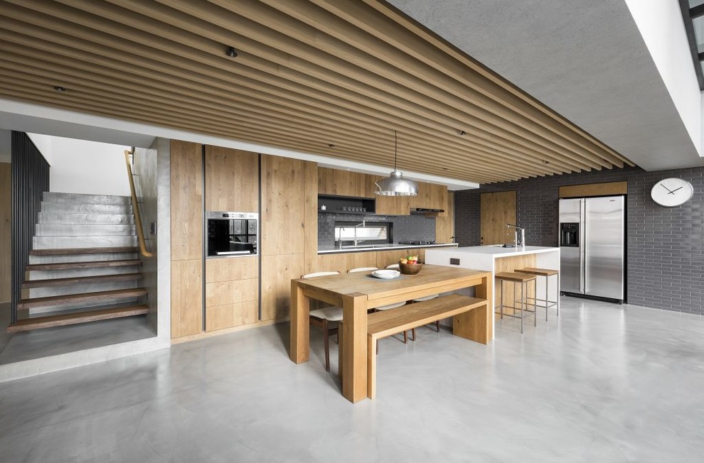 Exempel på ett mellanstort modernt linjärt kök med öppen planlösning, med skåp i ljust trä, bänkskiva i kvarts, rostfria vitvaror, betonggolv, en köksö och grått golv