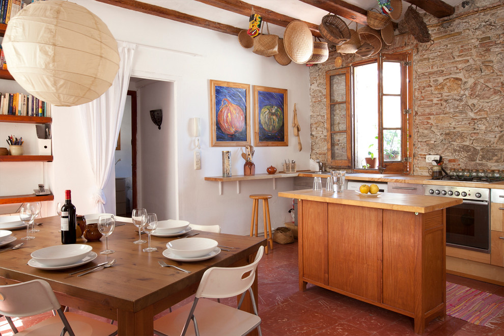 Zweizeilige, Mittelgroße Mediterrane Wohnküche mit Kücheninsel, flächenbündigen Schrankfronten, hellen Holzschränken, Arbeitsplatte aus Holz, Küchenrückwand in Braun, Küchengeräten aus Edelstahl, Keramikboden und Mauersteinen in Barcelona
