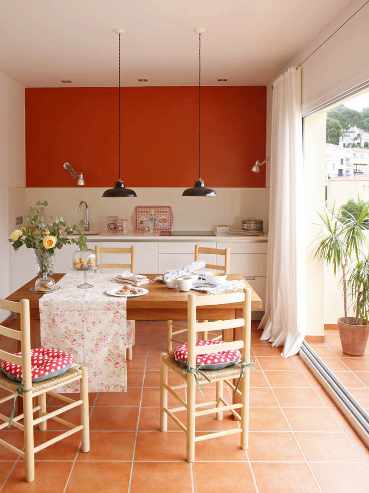 Modelo de cocina comedor mediterránea con armarios con paneles lisos, puertas de armario blancas, salpicadero beige, encimeras beige, fregadero bajoencimera y suelo naranja